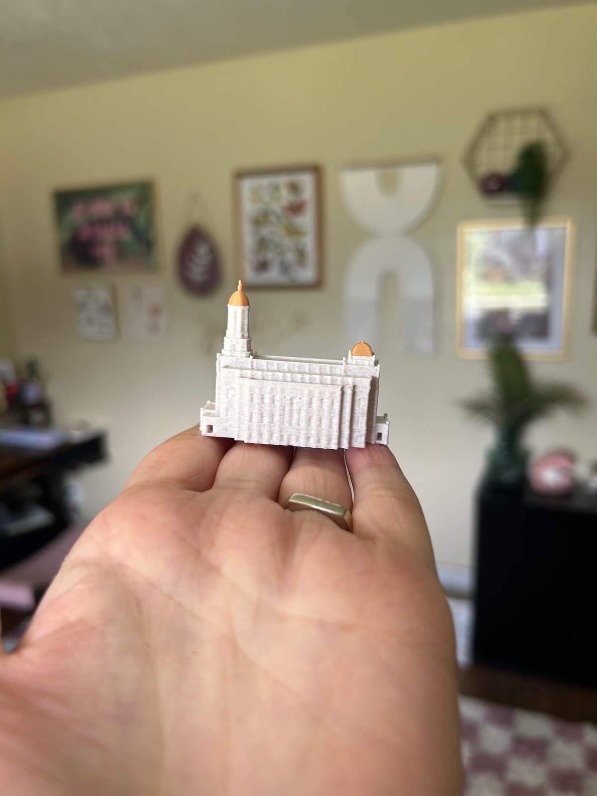 Tiny 2in Smithfield Utah Temple statue resting on fingertips, side view showing both gold domes
